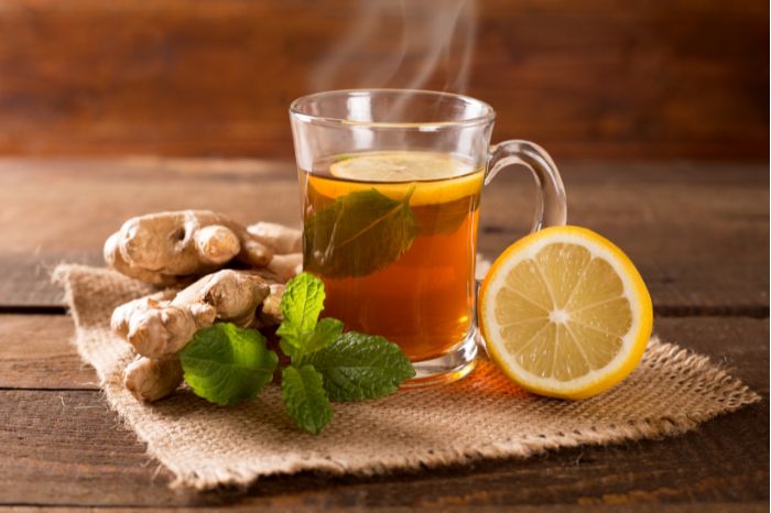 A cup of freshly brewed ginger tea with a slice of lemon on a wooden table